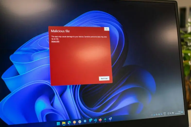 Kompiuterio darbalaukio ekranas ant kurio matoma iššokęs raudonas perspėjimo langas su tekstu "Malicious file" (liet. kenksmingas failas)