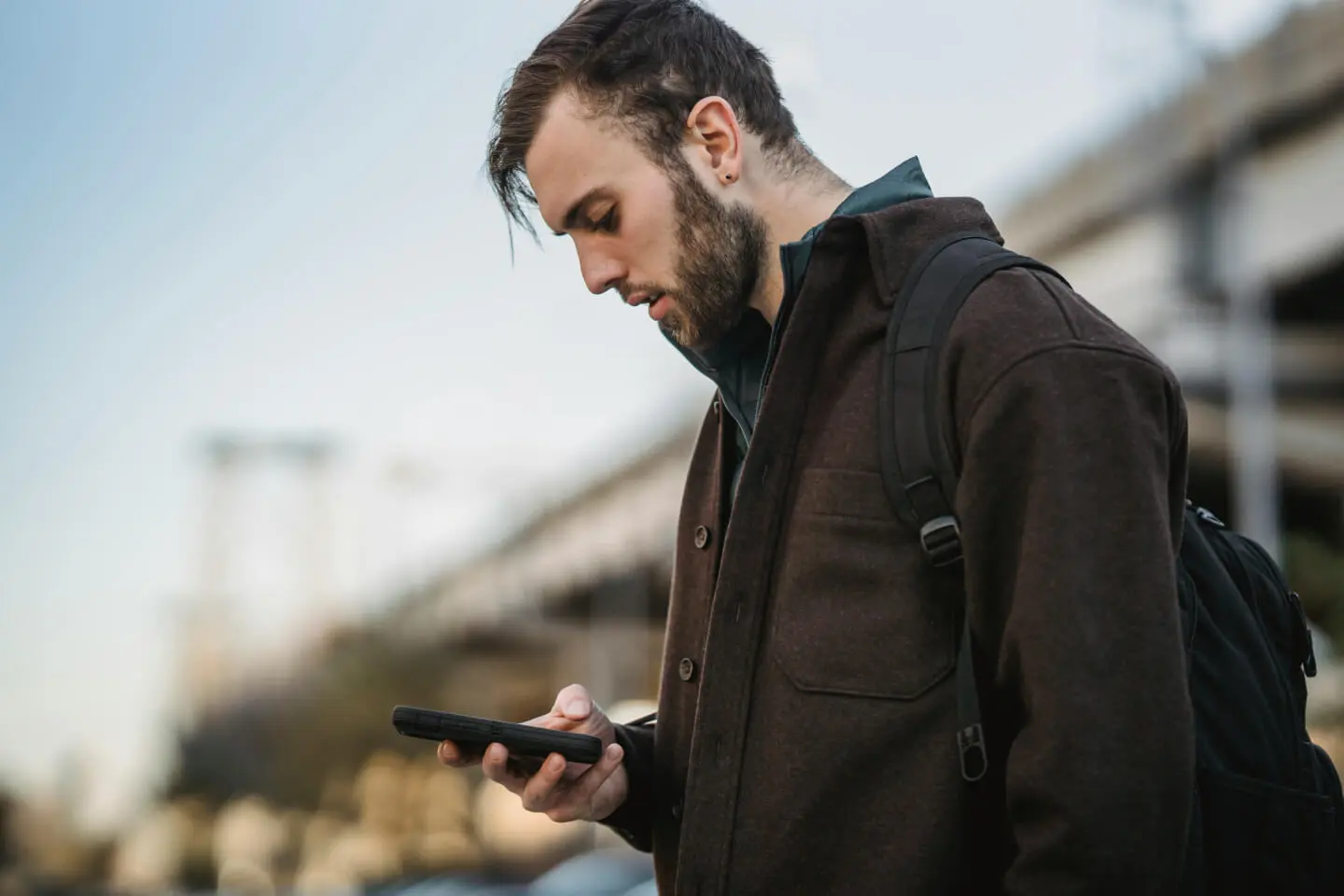 Vaikinas žiūri į išmanųjį telefoną