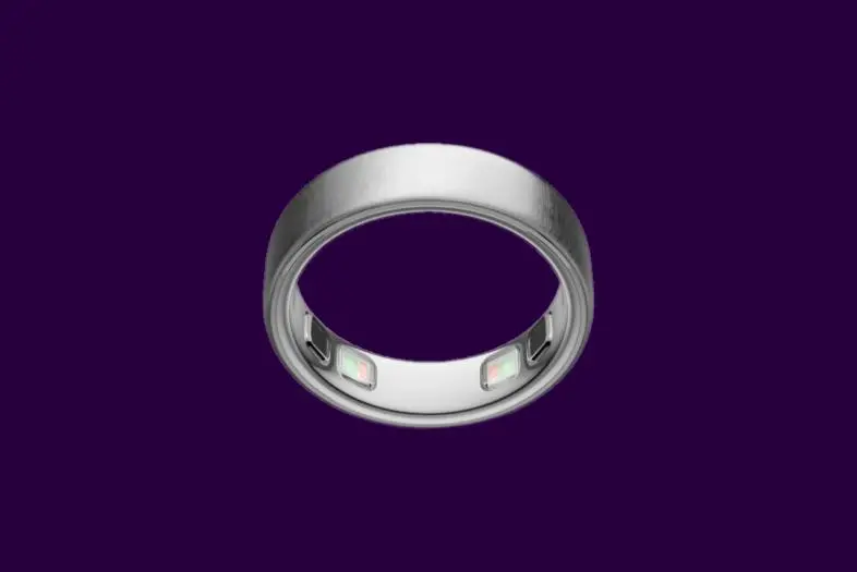 Metalinio dizaino „Oura Ring 5“ išmanusis žiedas violetiniame fone. Žiedas pasuktas taip, kad aiškiai matytųsi viduje integruoti sveikatos stebėjimo jutikliai.