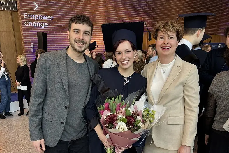 „Telia“ tvarumo specialistė Urtė universiteto diplomų teikimo ceremonijoje pozuoja bendrai nuotraukai su tvarumo komandos vadove Aurelija Žėkiene ir kitu kolega.