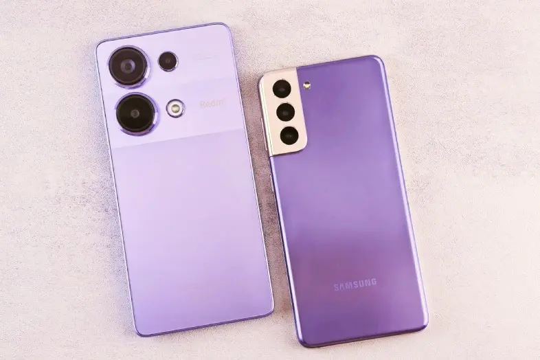 Šalia padėti du telefonai violetine nugarėle - vienas Xiaomi Redmi, kitas Samsung Galaxy.