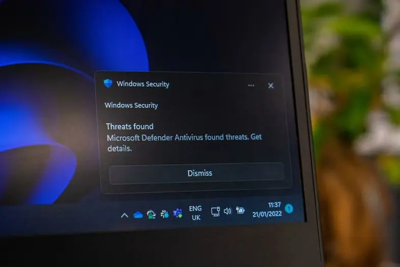 Kompiuterio ekrane rodomas „Windows Security“ pranešimas. „Microsoft Defender Antivirus“ aptiko grėsmių ir siūlo peržiūrėti išsamią informaciją.