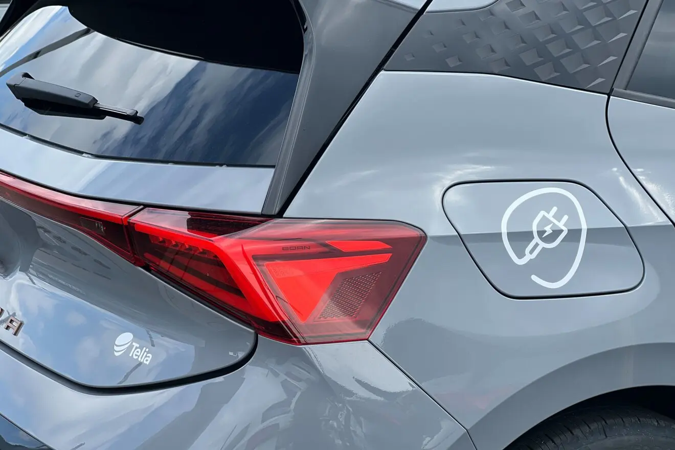 Telia priklausančio Cupra prekės ženklo automobilio galo šono nuotrauka. Ant automobilio matomi lipdukai su elektros kištuku bei Telia logotipu