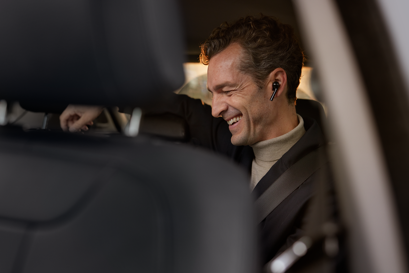 Vyras kalbantis per ausines automobilyje