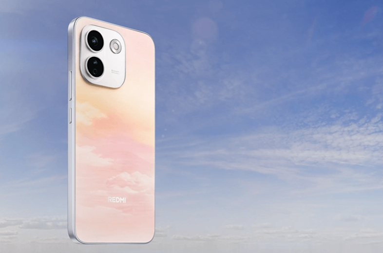 Ore tarsi pakibęs šviesus „Redmi“ telefonas su debesų rašto nugarėle. Fone matomas skaidrus mėlynas dangus, o telefono viršuje išsiskiria dvi galinės kameros.